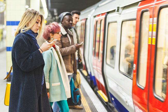 people using their phones while waiting for the tube
