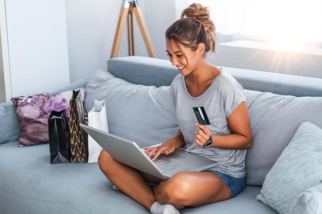A person sitting on a couch looking at a laptop.