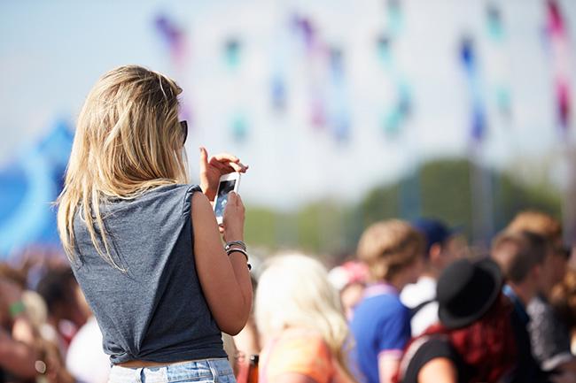A person looking at their phone outside at a festival.